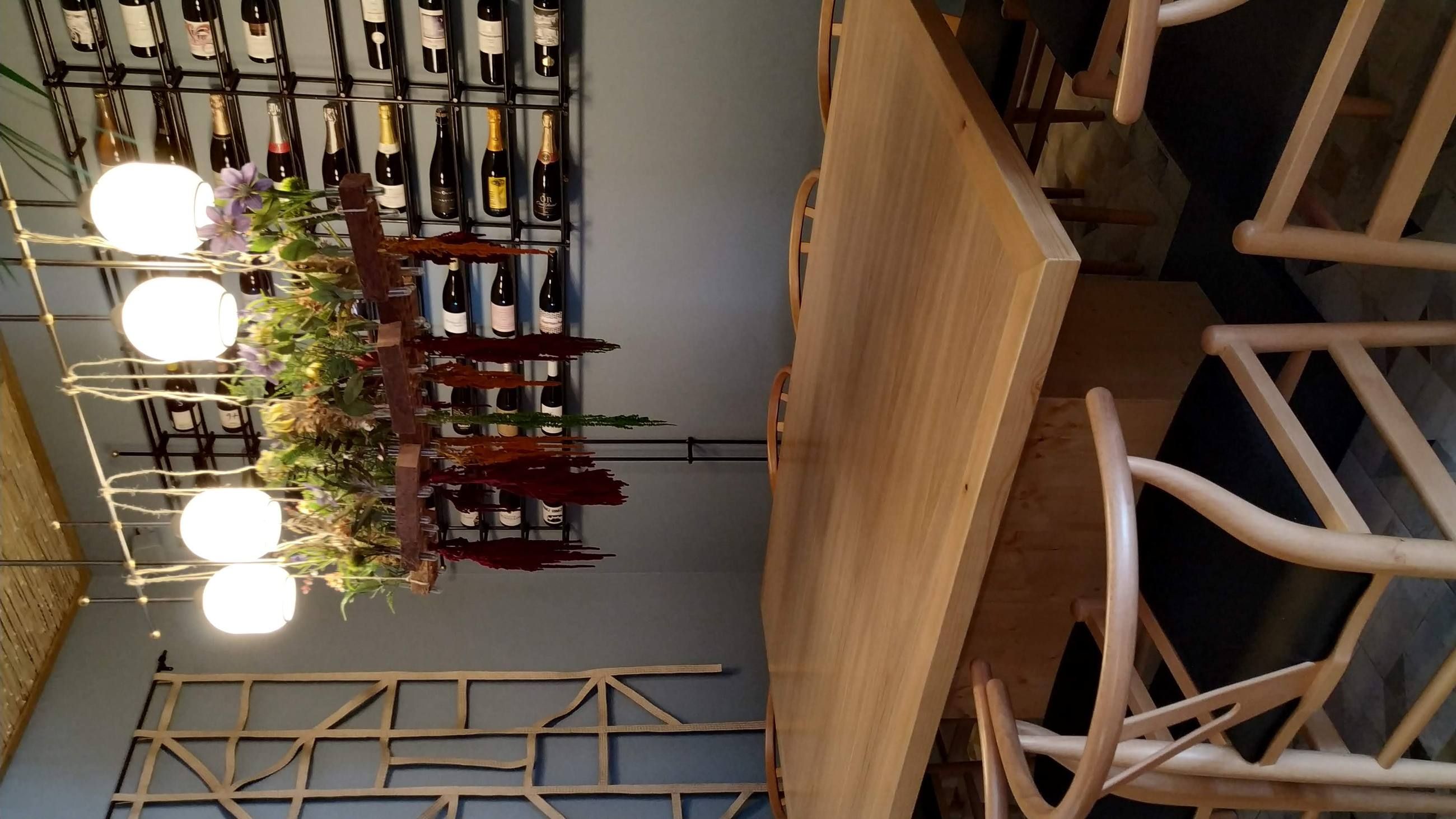 Mesa de madera maciza junto a una bodega expositora, bajo una lámpara colgante decorada