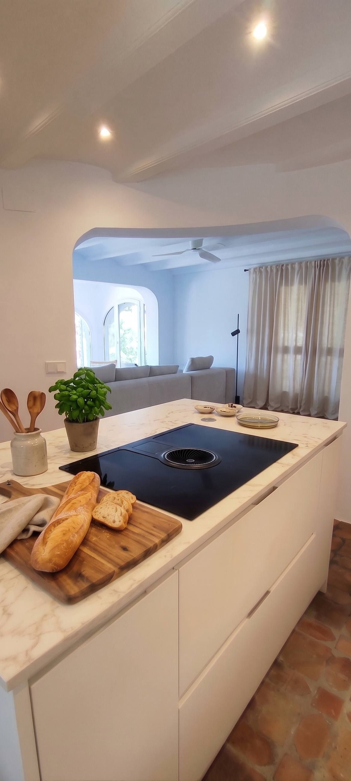 Isla de cocina a medida con encimera de mármol, pan recién horneado y albahaca fresca