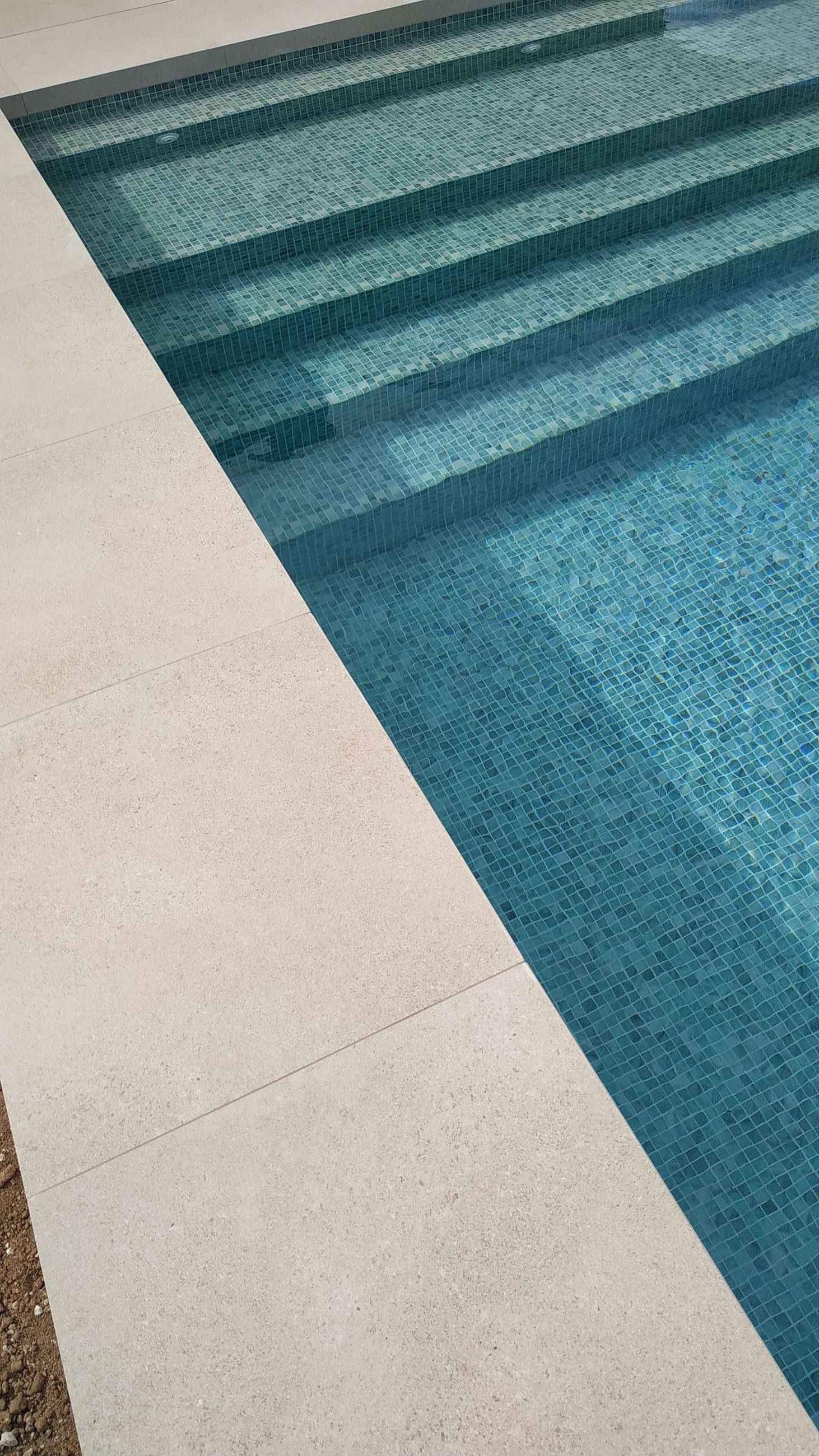 Detalle de los escalones de piscina en mosaico, junto al borde de piedra