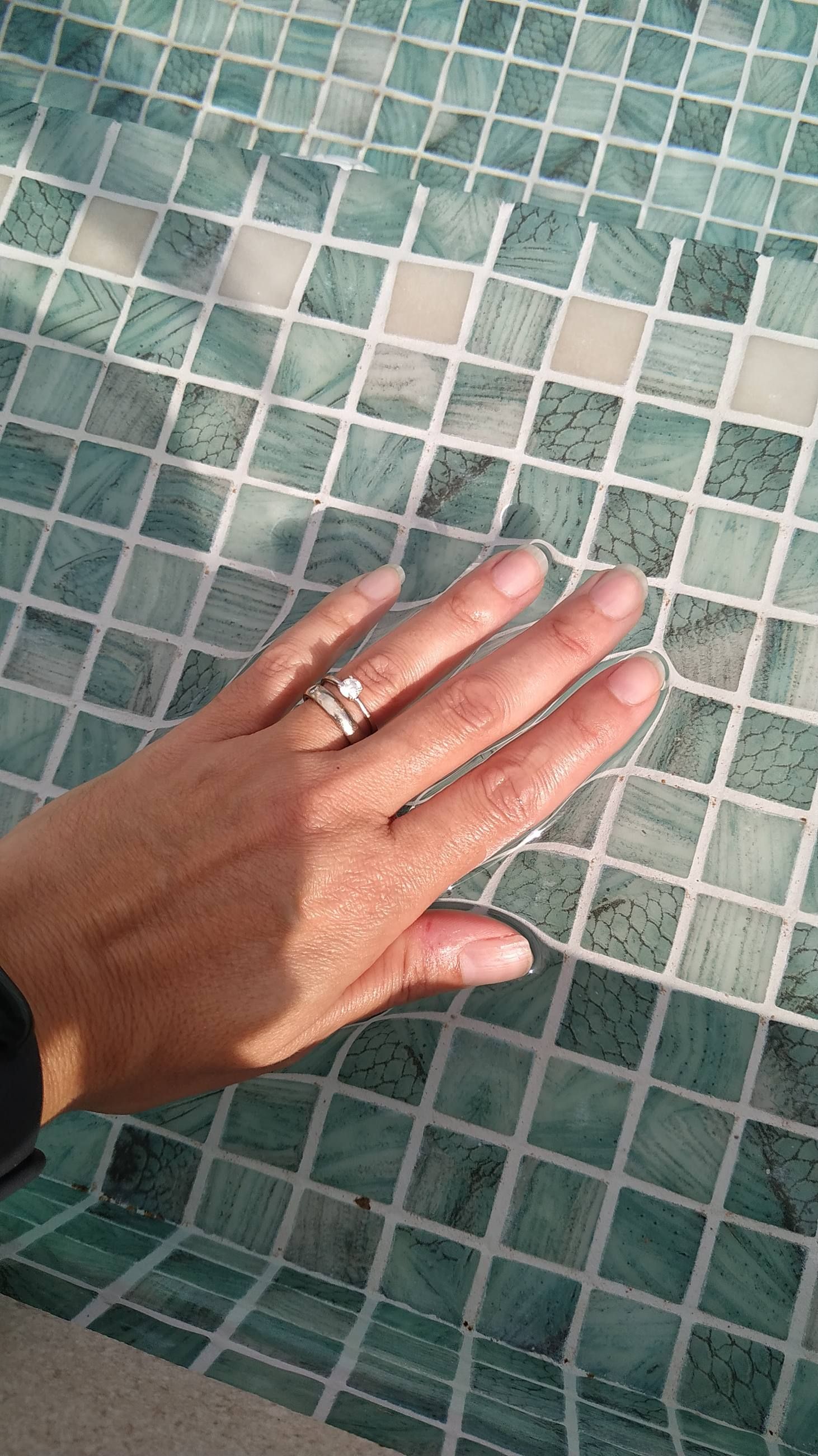 Detalle de una mano comprobando el acabado del mosaico de la piscina